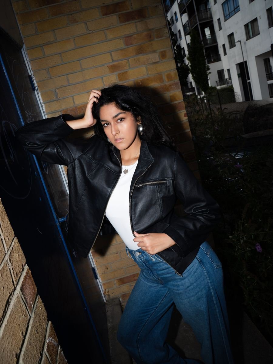 Night flash portrait in a brick alley, black leather jacket and wide jeans.