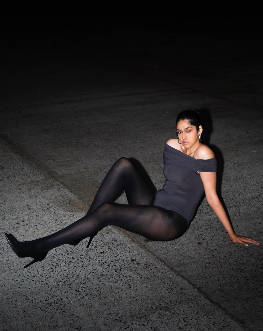 Flash portrait at night, sitting on concrete in black tights and heels.