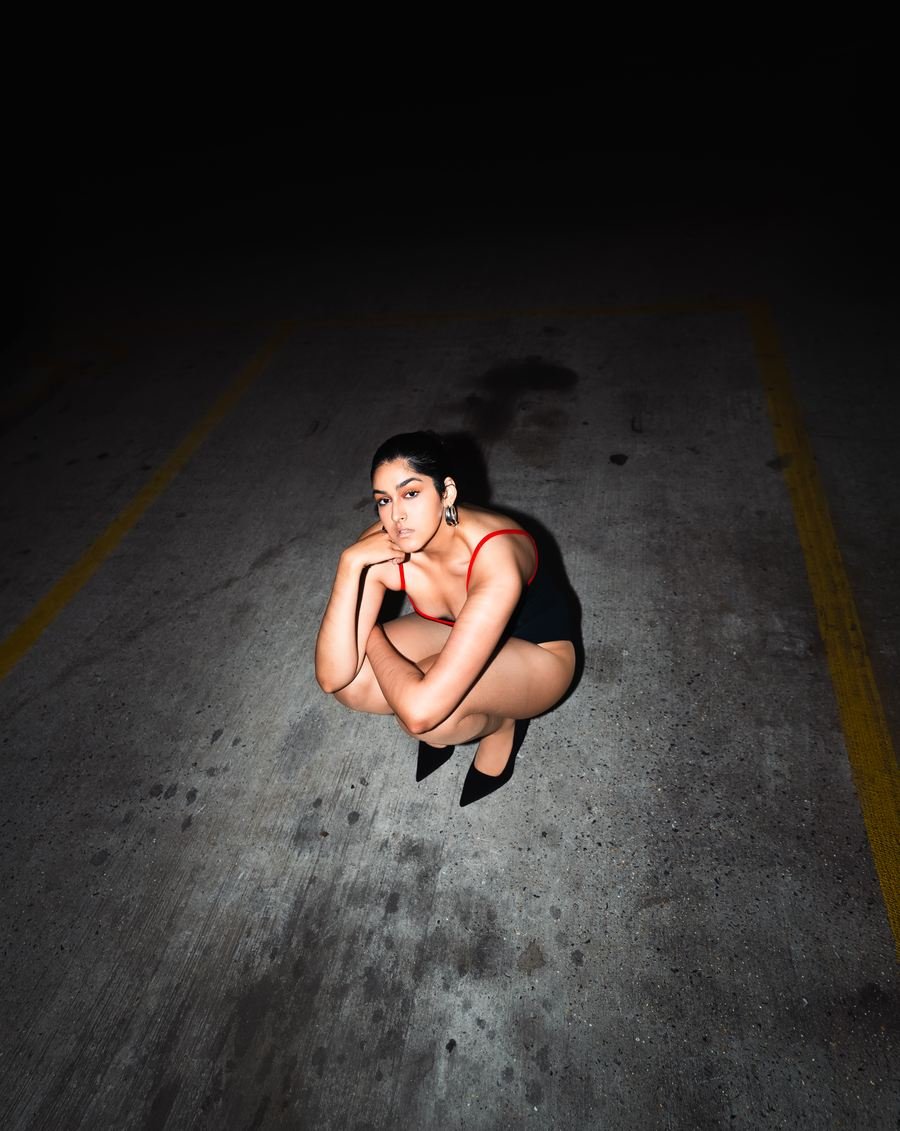 Flash portrait at night, crouched on a car park floor.